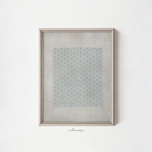 May include: A framed artwork featuring a square of blue floral pattern on a light gray background. The frame is a light silver color. The artwork is hanging on a white wall. The text "artive maze" is in the bottom right corner.