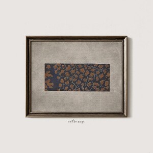 May include: A rectangular framed wall art piece featuring a dark navy blue fabric insert with a repeating copper-colored organic pattern. The frame is a metallic bronze color, and the background matting is a light beige, textured linen-like fabric.