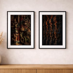 May include: Two rectangular wall art prints in black frames featuring detailed architectural carvings of figures in warm orange, deep red, and dark green tones. The left print shows ornate temple sculptures, while the right displays a repeating pattern.