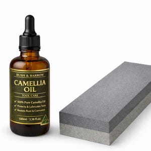 May include: A brown glass bottle of Camellia Oil with a black dropper, beside a grey sharpening stone. The label reads "BUSH & BARROW CAMELLIA OIL TOOL CARE". The bottle contains 100ml / 3.38 fl.oz. of oil.