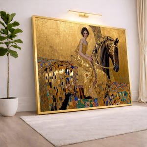 May include: A framed art print of a woman on a horse, rendered in gold and mosaic-like patterns. The artwork features a golden background and a woman in a gold dress. The horse is dark with gold accents. The frame is gold.