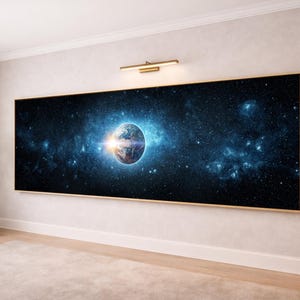 Puede incluir: Obra de arte enmarcada de gran tamaño que representa la Tierra en el espacio, con una luz brillante que emana de detrás del planeta. La obra está enmarcada en un marco dorado y cuelga de una pared de color neutro. Una planta en maceta y una lámpara de pie están en la habitación.