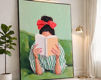 May include: A framed wall art print depicting a person with dark hair tied up with a large red bow, wearing a white and green striped shirt, reading an open book while lying on a green sofa against a light green background.