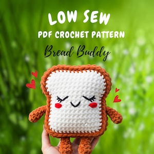 Può includere: Una fetta di pane all'uncinetto con un volto sorridente, braccia e gambe. Il pane è bianco con una crosta marrone e presenta occhi neri, ciglia e una bocca curva. Il testo "LOW SEW PDF CROCHET PATTERN Bread Buddy" è in alto.