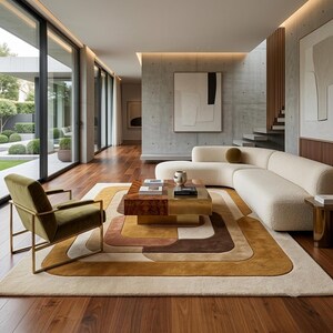 May include: A living room featuring a curved cream-colored sofa, an olive green armchair with a gold frame, and a square coffee table with a wood and brass finish. A large area rug with concentric brown, tan, and cream shapes sits on wood floors.
