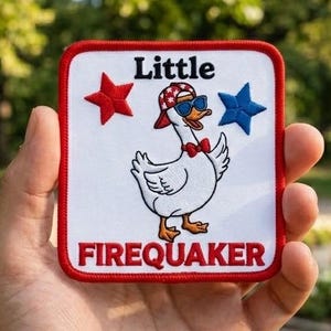 May include: A square embroidered patch with a white background and a red border. It features a cartoon duck wearing a red patterned cap, blue sunglasses, and a red bowtie. The text reads Little FIREQUAKER with a red star and a blue star.