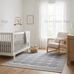 Puede incluir: Un cuarto de bebé con una cuna blanca, una alfombra estampada azul claro y una cómoda de madera. Un sillón beige está cerca de una ventana con cortinas blancas. Un móvil con formas de animales cuelga sobre la cuna.