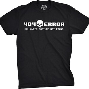 Puede incluir: Una camiseta negra de manga corta con texto pixelado en blanco que dice 404 ERROR y HALLOWEEN COSTUME NOT FOUND, con un icono de calavera pixelada situado entre los números 404 y la palabra ERROR en la parte frontal de la prenda.