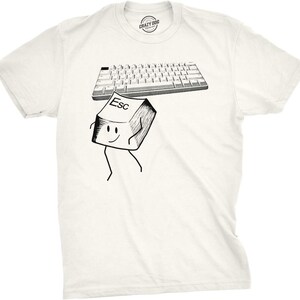 Op de afbeelding: Een crèmekleurig t-shirt met een zwart-witte afbeelding van een computertoetsenbord en een losse, antropomorfe 'Esc'-toets met armen en benen. De 'Esc'-toets is afgebeeld terwijl deze van het toetsenbord wegloopt. Het shirt heeft een ronde hals.