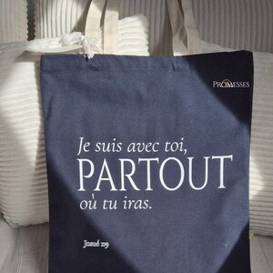 Peut inclure: Sac fourre-tout bleu marine avec le texte "Je suis avec toi, PARTOUT où tu iras" en blanc. Le sac a des anses beiges et le mot "PROMESSE" en blanc. Le texte "Josué 1:9" est en bas.