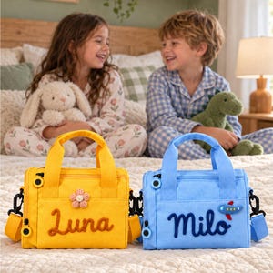 May include: Two rectangular lunch bags with top handles and detachable shoulder straps. The yellow bag features the name Luna in brown script and a small flower patch. The blue bag features the name Milo in dark blue script and an airplane patch.