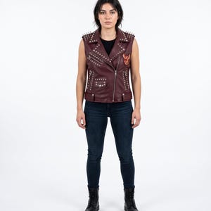 Damen-Bikerweste aus bordeauxrotem Leder mit Nietenbesatz und einem auffälligen Rückenaufnäher mit Phönixmotiv