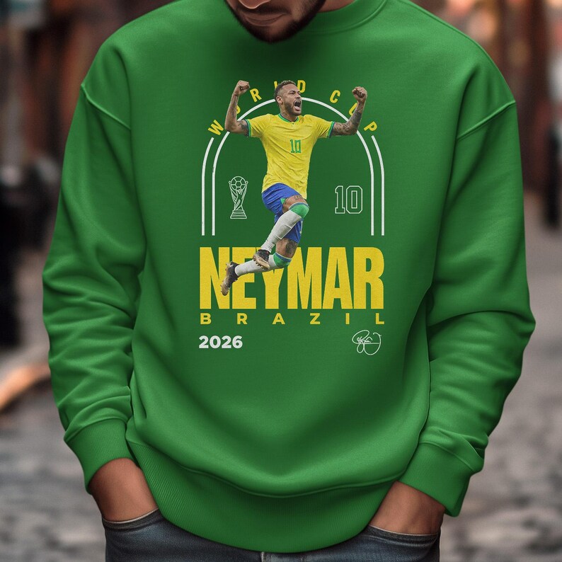 A man wearing a green sweatshirt with a graphic of a soccer player and text related to the World Cup.