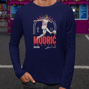 a man in a blue long-sleeved shirt with a graphic design depicting a soccer player in action.