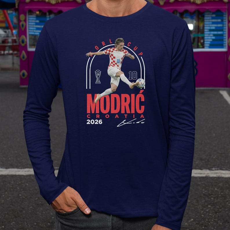 a man in a blue long-sleeved shirt with a graphic design depicting a soccer player in action.