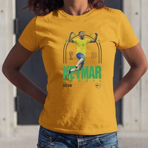 A yellow t-shirt with a graphic of a soccer player in mid-jump, celebrating with a raised fist.
