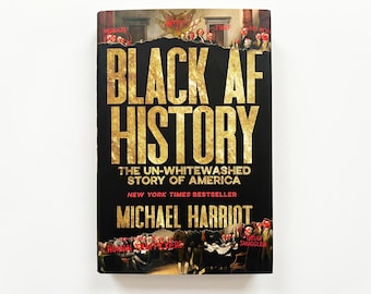 May include: A hardback book titled Black AF History: The Un-Whitewashed Story of America by Michael Harriot. The black cover features gold lettering and historical paintings at the top and bottom with red text labels like Mediocre, Thief, and Human Traffickers.