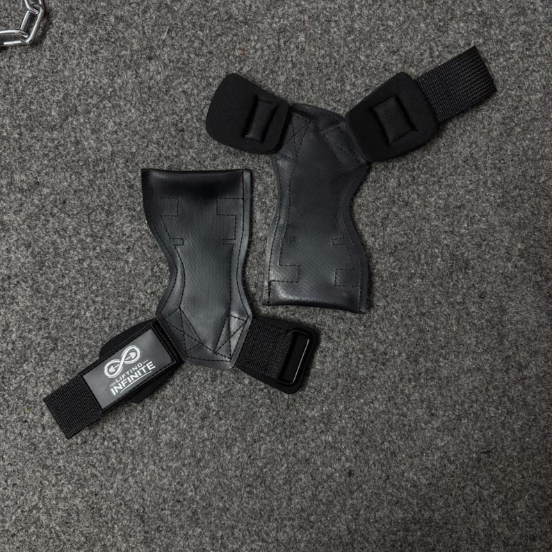 Puede incluir: Agarres de halterofilia negros con correas de mu&ntilde;eca ajustables. Los agarres est&aacute;n hechos de un material texturizado y presentan el texto "Lifting Infinite" en una de las correas. Dise&ntilde;ados para proteger las manos.