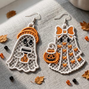 May include: A pair of white ghost-shaped earrings with orange embroidery. One ghost wears an orange hat and holds a boba tea cup. The other ghost wears an orange bow and carries a jack-o'-lantern bucket. Both feature silver-toned earring hooks.
