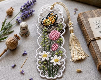 May include: A white lace bookmark featuring embroidered pink tulips, white daisies, and a monarch butterfly. The bookmark has a scalloped edge and a long, cream-colored tassel attached to the top with a small flower-shaped bead detail.