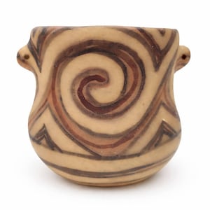 Op de afbeelding: Een kleine, beige keramische pot met een spiraalontwerp in bruin- en beigetinten. De pot heeft twee kleine handvatten en een afgeronde basis. Het ontwerp heeft een centrale spiraal en zigzagpatronen.