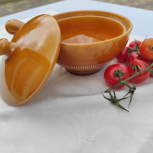 Op de afbeelding: Een set van drie keramische potten met deksels, met een geometrisch patroon in blauw, wit en grijs. De potten variëren in grootte, de grootste is ongeveer 20 cm hoog.