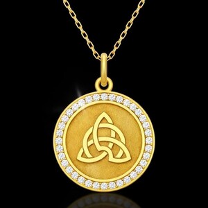 May include: A gold pendant necklace with a circular pendant displaying a Celtic knot design. The pendant is edged with small, clear gemstones. The necklace chain is gold, set against a black background.