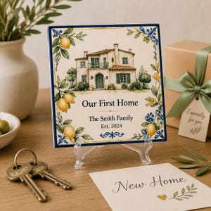 Peut inclure: Carreau de céramique carré avec une illustration de maison, des citrons et le texte "Our First Home". La tuile est sur un support transparent, avec des clés et une boîte cadeau en arrière-plan. Le texte indique "The Smith Family Est. 2024."