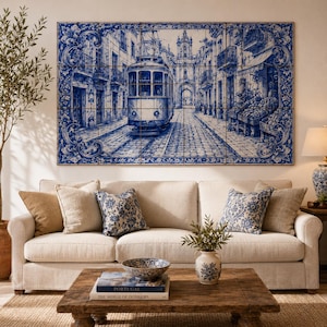 Pu&ograve; includere: Una grande opera d'arte murale raffigurante una scena piastrellata blu e bianca di una strada con un tram. L'opera d'arte &egrave; montata sopra un divano beige con cuscini fantasia. Un tavolino di legno con un libro e una ciotola decorativa &egrave; di fronte al divano.