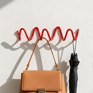 Peut inclure: Ensemble de trois mugs en céramique crème tachetée. Chaque mug présente un motif peint à la main : une feuille bleue et verte, une fleur jaune et une baie rouge. Les mugs ont une forme simple et arrondie.