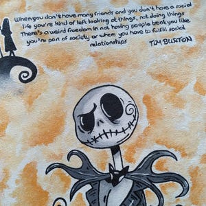 Puede incluir: Un bolso tote beige con una ilustración de Jack Skellington, una calabaza y una cita de Tim Burton. La obra de arte es en tonos negros, grises y naranjas. La cita dice: "Cuando no tienes muchos amigos..." y está en texto negro.