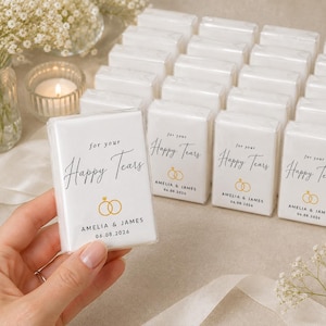 Può includere: Pacchetti di fazzoletti bianchi con la scritta "for your Happy Tears" e grafiche di fedi nuziali dorate. Ogni pacchetto è personalizzato con i nomi e la data del matrimonio di una coppia. Un romantico segnaposto.
