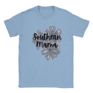 May include: Light blue t-shirt with the text "Southern Mama" in a cursive font, accompanied by a floral design in shades of gray. The shirt is made of a soft material and has short sleeves.