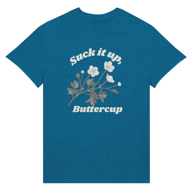 May include: Teal t-shirt with the text "Suck it up, Buttercup" in white script above a floral design. The floral design features white flowers and gray leaves. The t-shirt is a solid teal color.