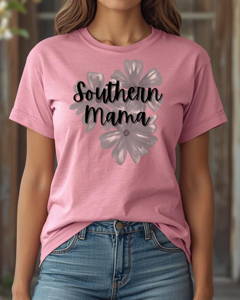 May include: A pink t-shirt with the text "Southern Mama" in black script, overlaid on a gray floral design. The shirt is short-sleeved and worn with blue jeans.