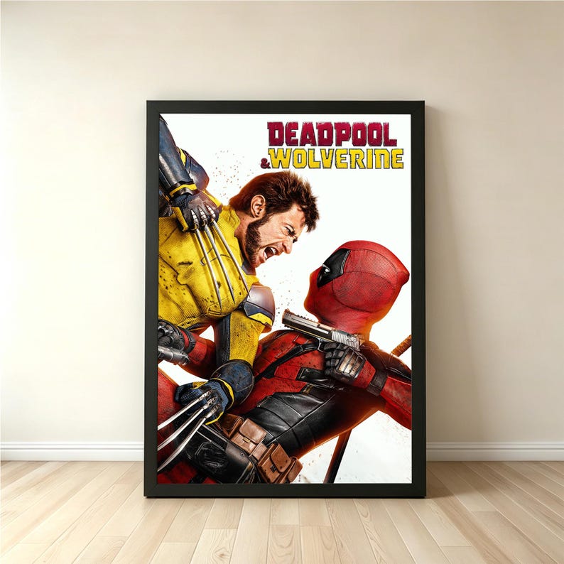 May include: A framed poster featuring Deadpool and Wolverine in a dynamic action pose. Deadpool, in his red suit, is aiming a gun, while Wolverine, in a yellow and blue suit, attacks with his claws. The poster's title reads "DEADPOOL & WOLVERINE".