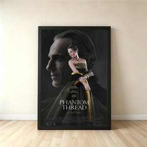 Può includere: Un poster incorniciato del film "Il filo nascosto" con Daniel Day-Lewis e una donna in un abito verde e oro. Il poster ha una cornice nera ed è esposto contro un muro neutro.