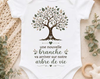 May include: A white short-sleeved baby bodysuit featuring a graphic of a tree with green and brown leaves. Below the tree, the text reads: une nouvelle branche va arriver sur notre arbre de vie, accompanied by small heart and leaf illustrations.