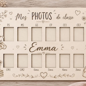 Può includere: Una tavola rettangolare in legno chiaro con dodici ritagli rettangolari per foto. La tavola è incisa con il testo "Mes PHOTOS de classe" e il nome "Emma", insieme a etichette per i gradi scolastici e illustrazioni di un orsacchiotto, fiori e uno zaino.