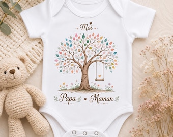 May include: A white short-sleeved baby bodysuit featuring a central graphic of a tree with multicolored leaves, a swing, and a heart carved into the trunk. The text Moi is printed above the tree, and Papa Maman is printed below the tree.