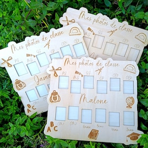Op de afbeelding: Drie lichtgekleurde houten borden voor schoolfoto's, elk gegraveerd met de tekst "Mes photos de classe", leerjaar-labels en iconen van een schaar, geodriehoek, rugzak, wereldbol, boek en afstudeerhoed, voorzien van rechthoekige uitsparingen.