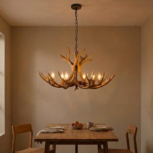 Puede incluir: Una lámpara de araña decorativa con forma de cuernos de ciervo, con múltiples bombillas, cuelga sobre una mesa de comedor de madera. La lámpara está suspendida por una cadena oscura. La habitación tiene un ambiente cálido, con paredes neutras y una mesa de madera.