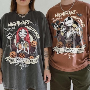 May include: Two people wearing oversized t-shirts with "Nightmare Before Christmas" graphics. One shirt is dark gray with "The Pumpkin Queen" and Sally, the other is brown with "The Pumpkin King" and Jack Skellington. Both shirts have pumpkin and spiderweb details.
