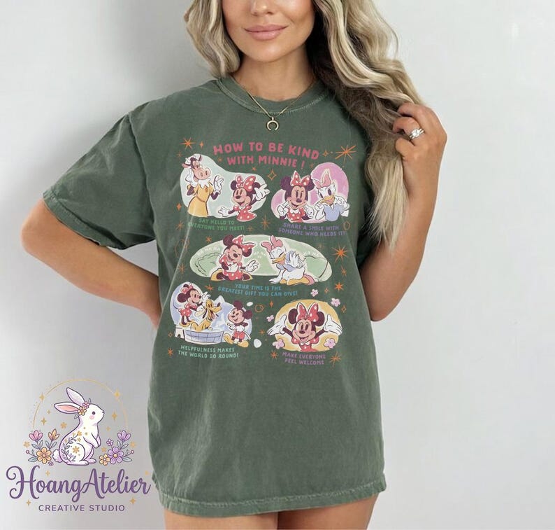 May include: Olive green t-shirt with a graphic of Minnie Mouse and friends, and the text "HOW TO BE KIND WITH MINNIE!". The design includes illustrations of Minnie, Daisy, and other characters. The shirt also has the Hoang Atelier logo.