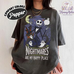 May include: Dark grey t-shirt with a graphic of Jack Skellington, ghosts, and the text "NIGHTMARES ARE MY HAPPY PLACE." The shirt has a distressed look and the word "Pepper" is printed on the top left. The design is from The Nightmare Before Christmas.