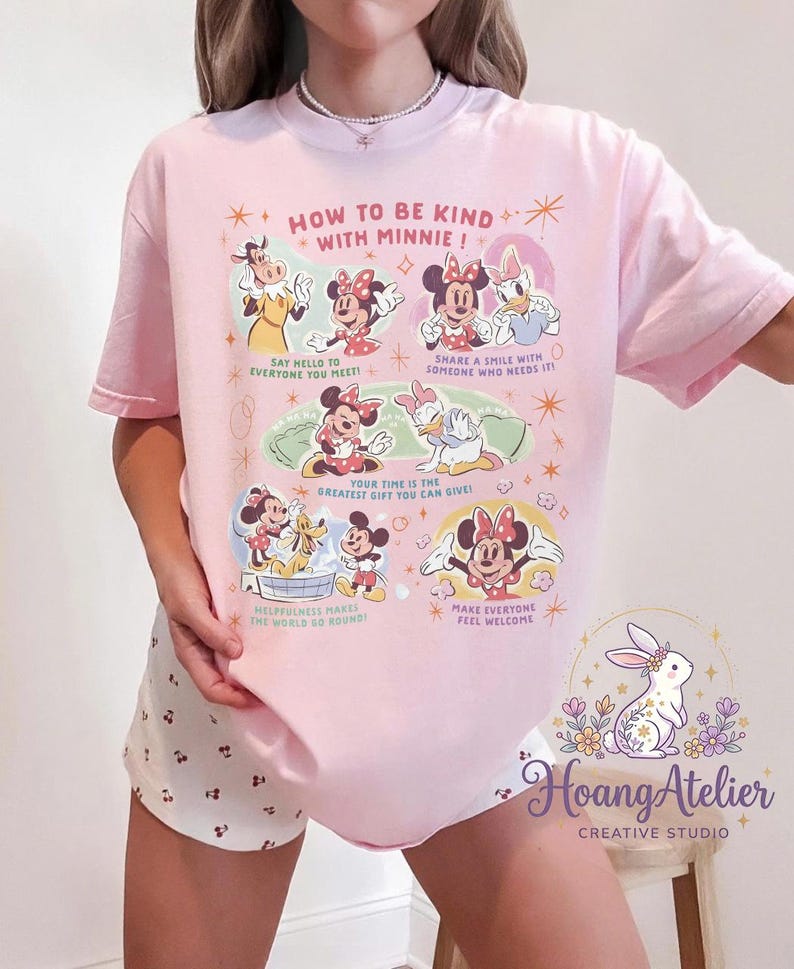 May include: Pale pink t-shirt with Minnie Mouse and friends, displaying the text "HOW TO BE KIND WITH MINNIE!". The design includes illustrations and phrases such as "Say hello to everyone you meet!" and "Make everyone feel welcome."