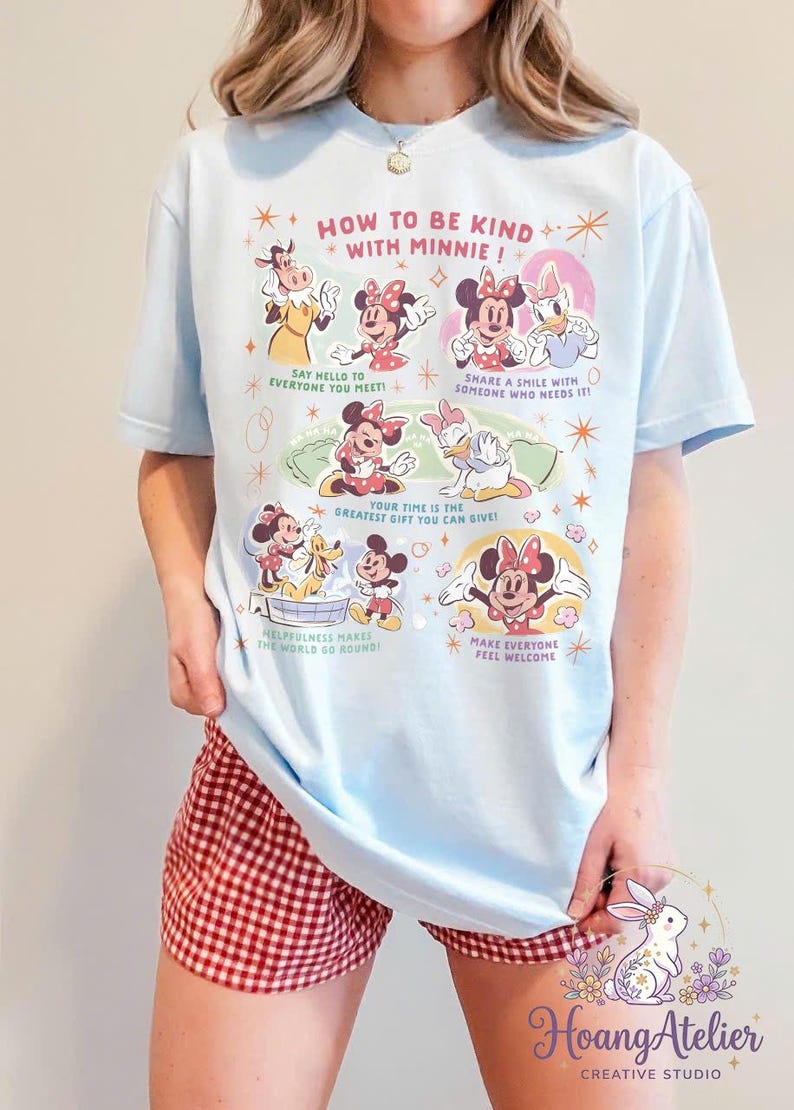 May include: Pale blue t-shirt featuring the text "HOW TO BE KIND WITH MINNIE!" and images of Minnie Mouse and friends. The shirt also has the text "SAY HELLO TO EVERYONE YOU MEET!" and "SHARE A SMILE WITH SOMEONE WHO NEEDS IT!"
