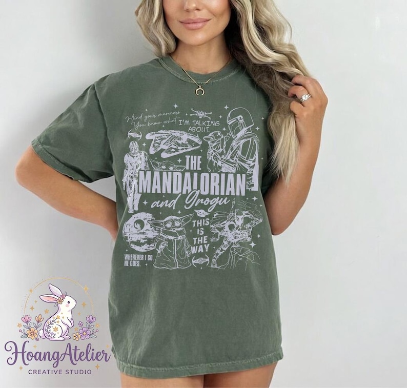 Puede incluir: Camiseta verde oliva con el texto "THE MANDALORIAN and Grogu" e ilustraciones de personajes de la serie. La camiseta tambi&eacute;n incluye las frases "This is the Way" y "Wherever I Go, He Goes."