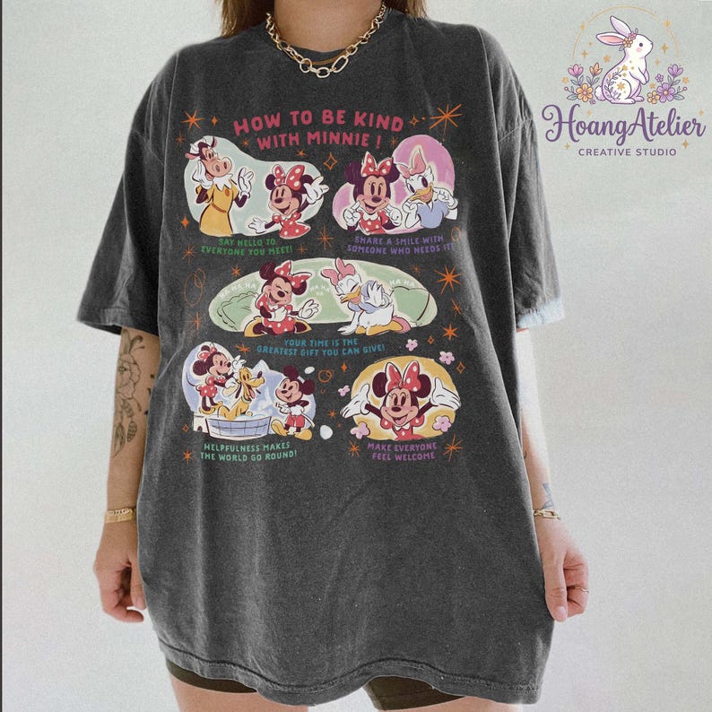 May include: Dark grey t-shirt with Minnie Mouse and friends, and the text "HOW TO BE KIND WITH MINNIE!". The shirt features illustrations of Minnie, Daisy, and other characters with positive messages. The Hoang Atelier logo is in the upper right corner.