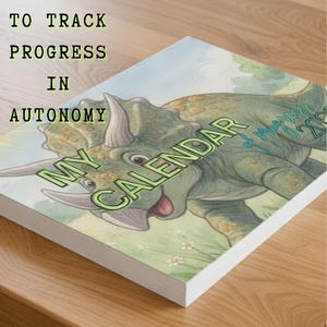 May include: A calendar with a triceratops illustration. The cover reads "My Calendar" and "2023" with the text "A Calendar to Track Progress in Autonomy". The calendar is on a wooden surface.
